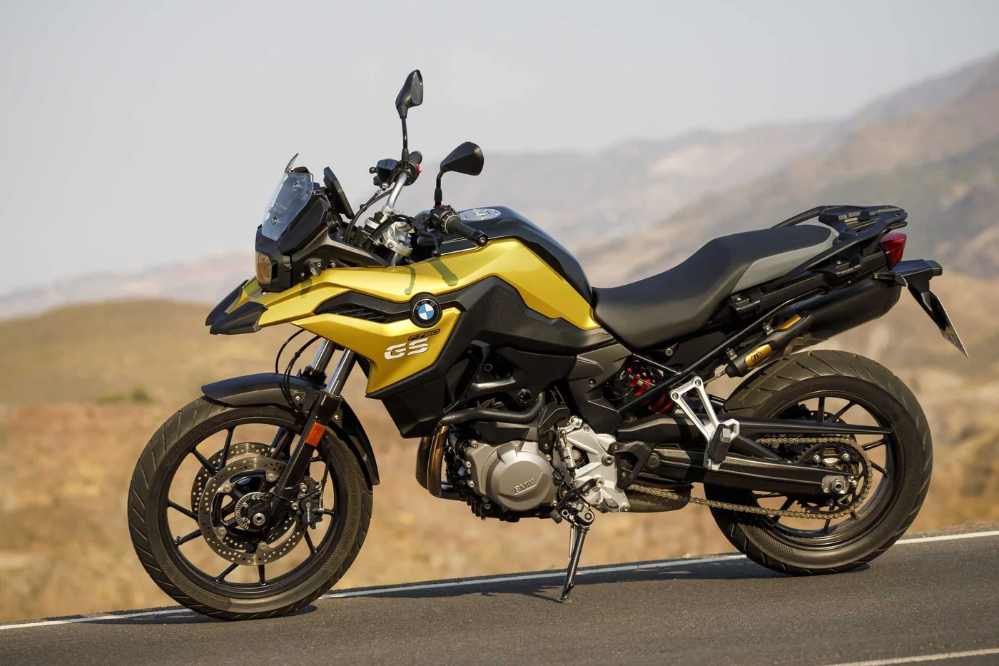 BMW F 750 GS amarela parada em estrada, com montanhas ao fundo