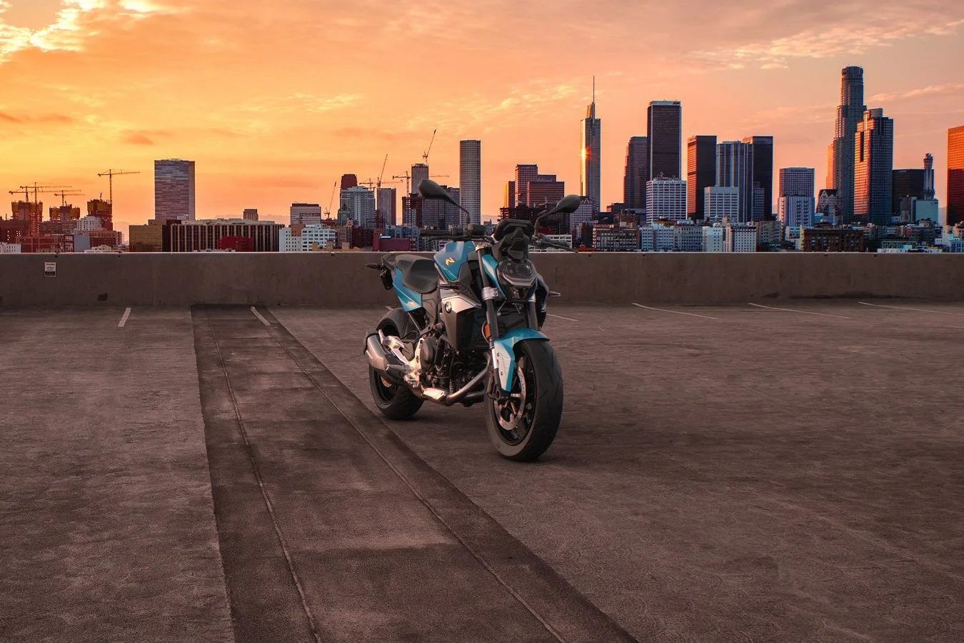BMW F 900 R azul estacionada em terraço com a silhueta da cidade ao fundo