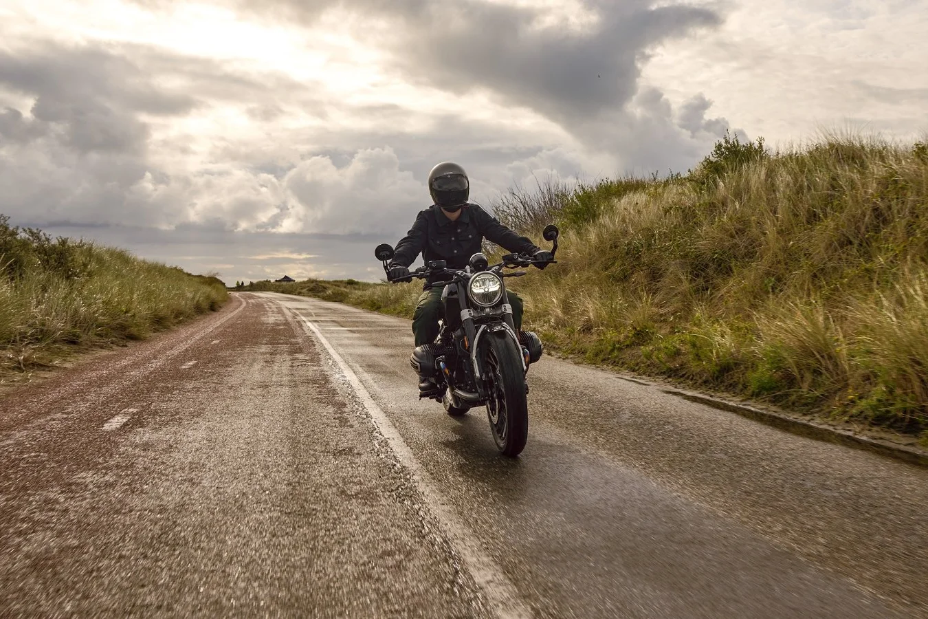 BMW R 12 clássica rodando em estrada de terra ladeada por capim