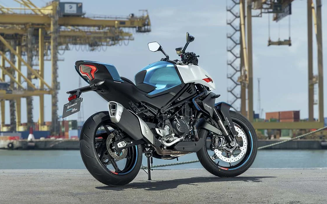 CFMOTO 450 NK branca e azul-petróleo estacionada em área portuária